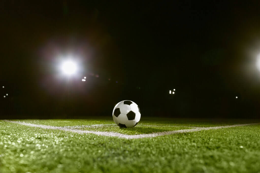 A soccer ball sitting on a field at night under the lights